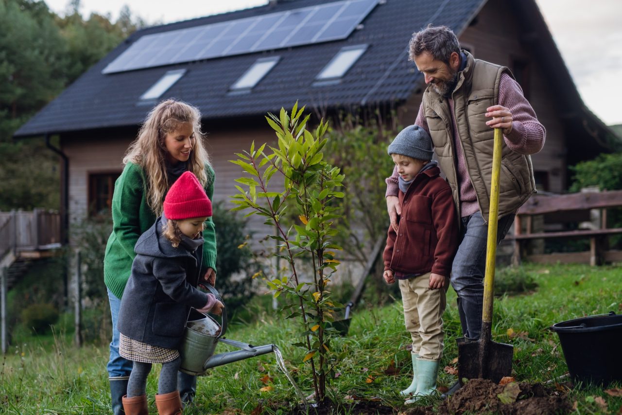 young-family-taking-care-of-home-garden-planting-tree-mother-father-and-kids-spending-time.jpg